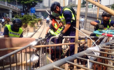 Cảnh sát Hồng Kông phải dùng máy cắt khóa để tháo dỡ hàng rào trên đường phố.