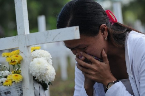 Một người phụ nữ nghẹn ngào trước ngôi mộ tập thể nơi chôn vùi 2000 người ở ngoại ô Tacloban.