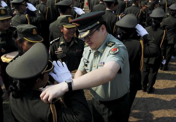 Một viên Trung tá quân đội Trung Quốc gắn quân hàm cho học viên sĩ quan quân sự Campuchia trong lễ tốt nghiệp. Ảnh: Reuters.