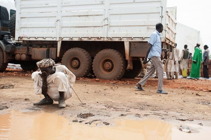 Một người dân Sudan phải uống nước từ vũng lầy trên đường. Ảnh: IBTIMES.