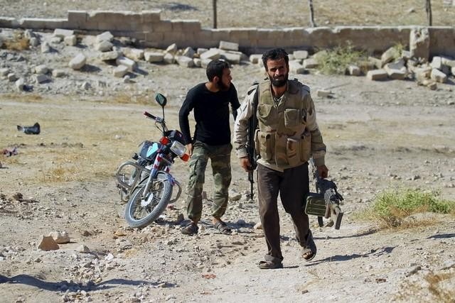 2 thành viên phe đối lập Syria trước cảnh hoang tàn đổ nát sau các cuộc không kích. Ảnh: Reuters.