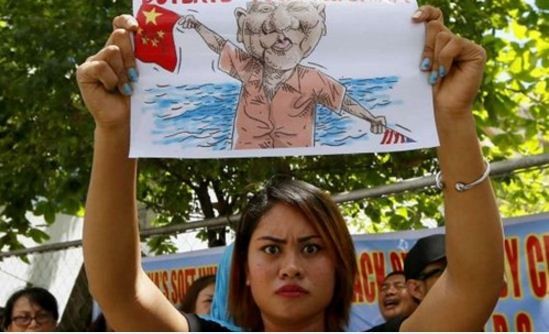 Một người dân Philippines mang theo tranh biếm họa tới cổng đại sứ quán Trung Quốc tại Manila tuần hành phản đối hành động của Trung Quốc ở Biển Đông và rãnh Benham. Ảnh: AP.