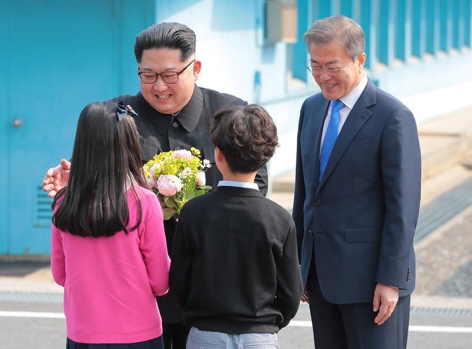2 trẻ em Hàn Quốc tặng hoa ông Kim Jong-un ngay khi nhà lãnh đạo Triều Tiên &quot;vượt biên&quot; qua Vĩ tuyến 38. Ảnh: The New York Times.