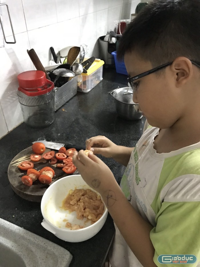 Em Nguyễn Đăng Sỹ Hoàng đang giúp mẹ nấu cơm trưa (Ảnh: Sơn Quang Huyến)