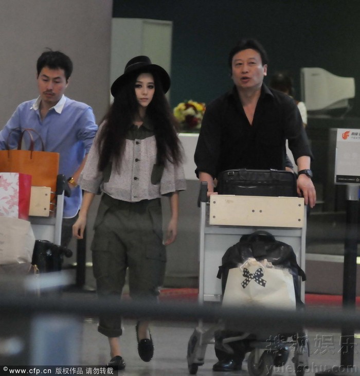 Xuất hiện tại sân bay Hồng Kiều, Thượng Hải, Phạm Băng Băng gây ấn tượng bởi phong cách thời trang khá hầm hố quần lửng túi hộp, mũ rộng vành, mái tóc dài được đánh rối rất lạ mắt… Trong ảnh:Phạm Băng Băng cùng quản lý Mục Hiểu Quang