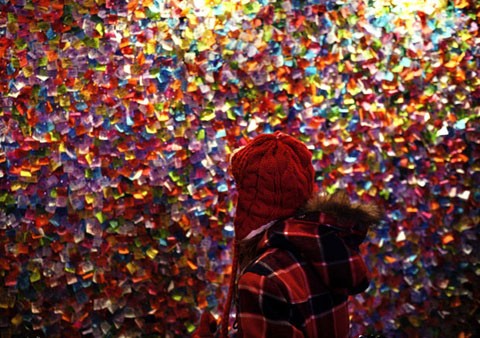 Một em nhỏ đứng ngắm bức tường dán những điều ước trong năm mới tại quảng trường Thời đại, Mỹ. Những mẩu giấy ghi lại những mong muốn của người dân trên toàn thế giới sẽ được thổi tung lên vào đúng thời khắc giao thừa, trong chương trình đón năm mới ở New York.
