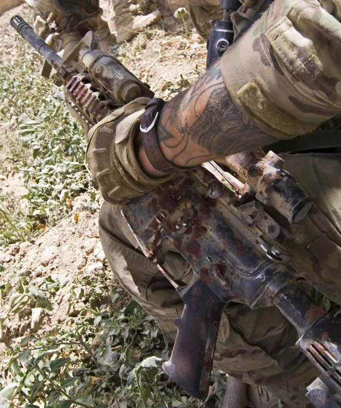 Afghanistan (ngày 12 tháng 6 năm 2012: Một lính Mỹ cầm khẩu súng trường M4 đầy máu của đồng đội sau khi anh ta bị thương bởi một thiết bị nổ tự chế (IED) trong một cuộc tuần tra ở miền nam Afghanistan.