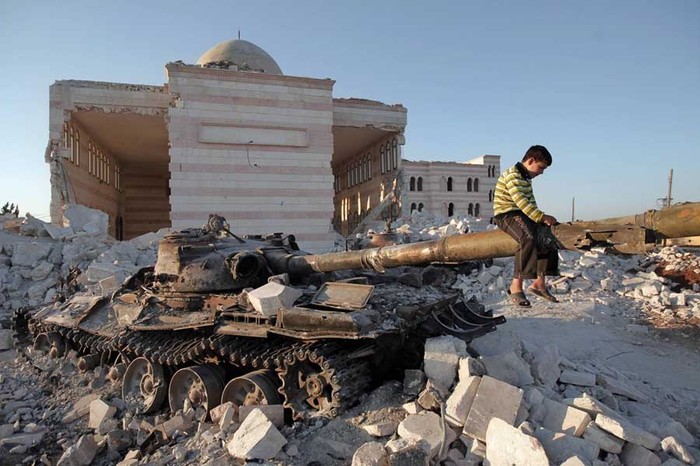 Một cậu bé trên khẩu pháo của một chiếc xe tăng quân đội Syria bị phá hủy trong đống đổ nát của nhà thờ Hồi giáo Azaz phía Bắc thành phố Aleppo.