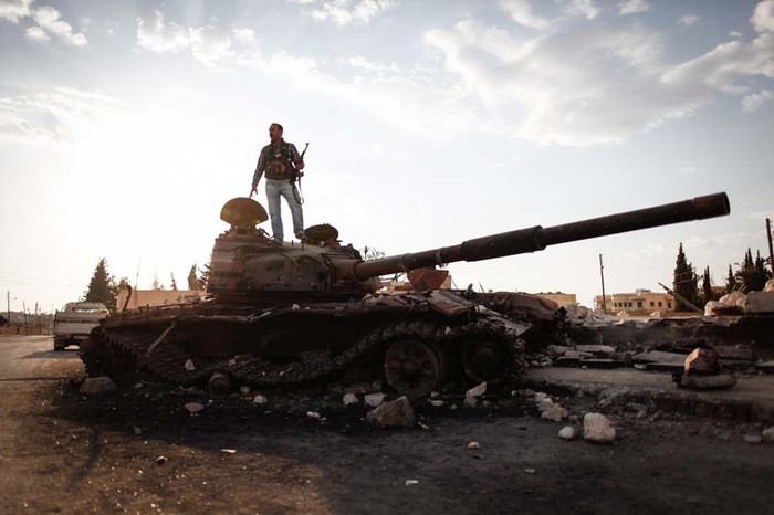 Syria (10/9): Một thành viên thuộc Lực lượng Quân đội Tự do Syria trên một chiếc xe tăng bị phá hủy của quân đội Syria.