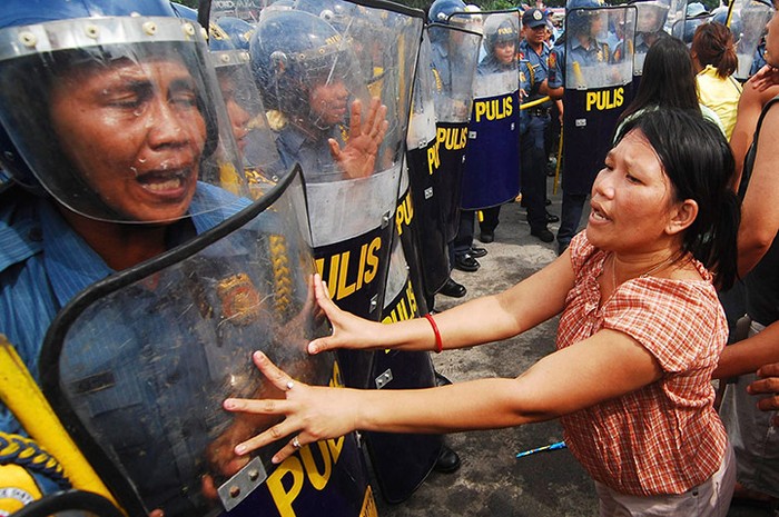 Những người định cư bất hợp pháp xung đột với cảnh sát tại đại lộ Commonwealth ở thành phố Quezon, Philippines. Hơn 1000 gia định sống trên khu đất bì giải tỏa để xây dựng một trung tâm thương mại mới