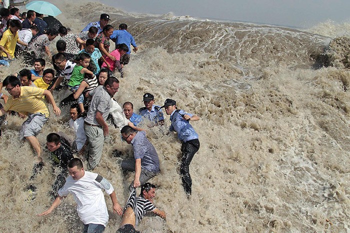 Cảnh sát và người dân chạy khi thủy triều tràn qua bờ sông Qiantang ở Haining, Trung Quốc
