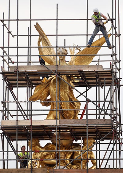 Các công nhân đang dựng giàn giáo xung quanh tượng thần Chiến thắng trên đỉnh đài tưởng niệm Nữ hoàng Victoria ở London, Anh. Đài tưởng niệm này đang trong thời gian tu sửa