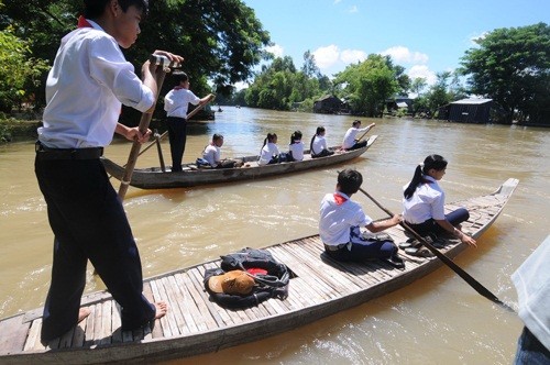 Tại huyện đầu nguồn lũ An Phú (An Giang), ngày khai giảng ở ba xã giáp biên giới với nước bạn Campuchia có trên 900 học sinh là con em Việt kiều đi xuồng, đò để đến trường. Ảnh: Tuổi Trẻ