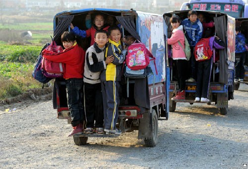 Học sinh bám vào đuôi một chiếc xe khi được đưa về nhà ở thị trấn Tongyang, tỉnh An Huy ngày 21/11. Những chiếc xe này chỉ dành cho 4 người ngồi nhưng đã nhét hàng chục đứa trẻ.