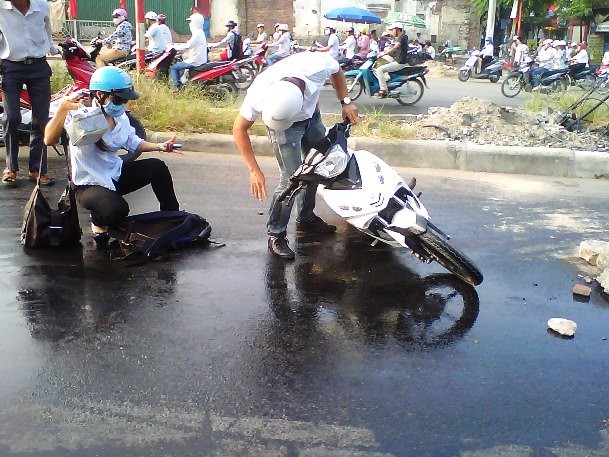 Hai người đi xe máy này bị ngã do vệt dầu trơn trượt để lại.
