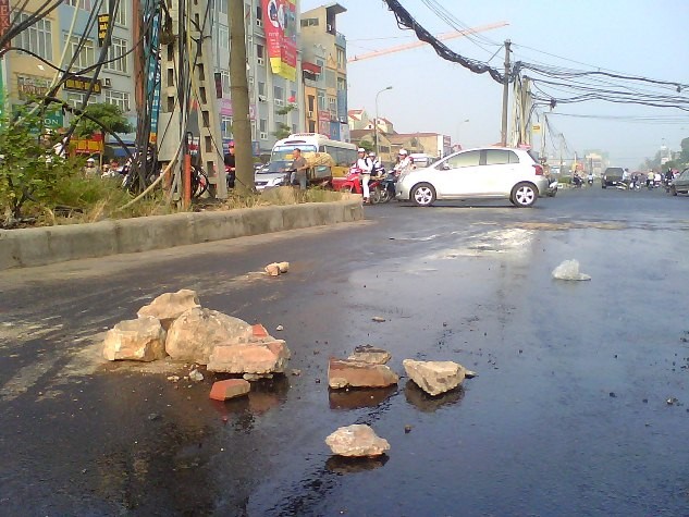 Người dân đã phải bỏ những viên đá, gạch vỡ ra đoạn đường để cảnh báo người tham gia giao thông.