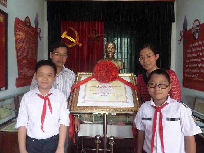 Khánh và Nam chụp ảnh cùng cô giáo chủ nhiệm và thầy Việt tại phòng truyền thống của trường