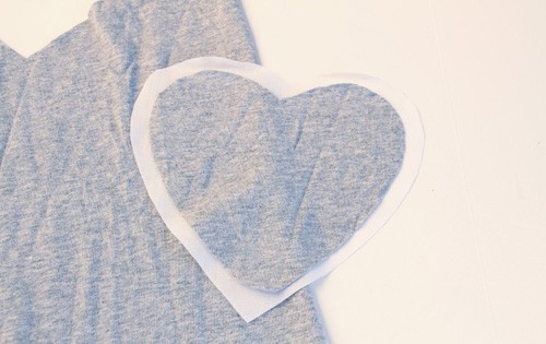 Đặt trái tim vừa cắt lên tấm vải trắng và cắt thành hình trái tim mới lớn hơn trái tim mẫu 1 cm.