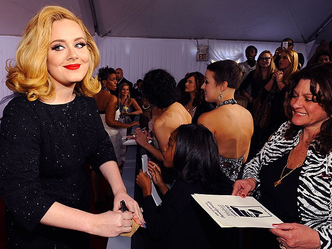 Adele đang ký tặng fan nhưng mắt lại quay sang phía phóng viên ảnh để tạo dáng