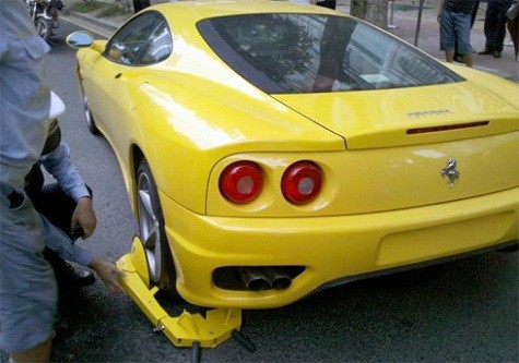 Siêu xe Ferrari 360 đỗ sai luật và không có biển số trên một con phố ở Quảng Châu (Trung Quốc), bằng đấy lỗi đủ để nó bị "cùm chân". Nhưng viên cảnh sát giao thông này đã có một ngày không mấy suôn sẻ khi chiếc khóa càng của Trung Quốc quá nhỏ so với chiếc bánh của siêu xe. Ảnh: Carnewschina.