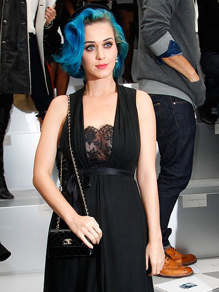 Katy Perry tiếp tục diện mái tóc xanh bồng bềnh tới tham dự show thời trang của Chanel tại Paris. Cô mặc một chiếc váy đen có phần ren mỏng ở ngực, lấp ló khoe gò bồng đảo. Cô cùng diện một chiếc clutch xinh xắn bằng da bóng của Chanel