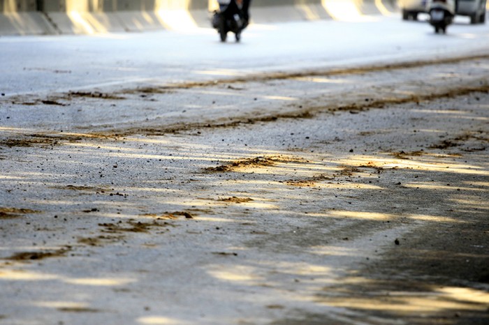 Mặt đường Phạm Văn Đồng nhiều đoạn vương vãi đất cát do xe tải chở đất, cát để lại sau mỗi lần rơi vãi