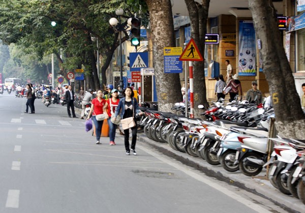Không còn chỗ đi trên vỉa hè, người đi bộ phải "nhào" xuống lòng đường để tránh bãi gửi xe trước trụ sở Bưu điện Hà Nội