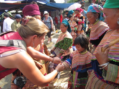 Một du khách nước ngoài tặng vòng đeo tay cho trẻ em dân tộc.