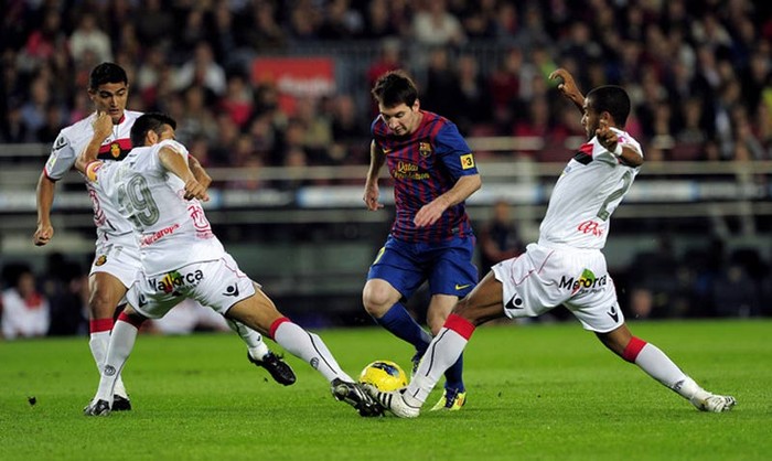 Hai cầu thủ Mallorca cùng lao vào tranh bóng với Lionel Messi trong trận đấu tại La Liga