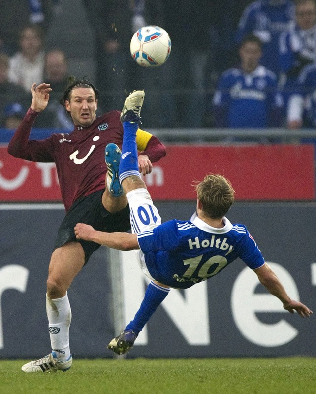 Christian Schulz (áo nâu) của Hannover tranh bóng với Lewis Holtby (Schalke 04) trong trận đấu ở Bundesliga