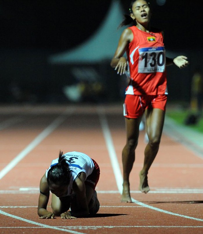 Triyaningsih (trái) của Indonesia hôn đất trong lúc Thet Phya (Myanmar) chạy qua sau khi đoạt huy chương Vàng ở nội dung chạy 5.000m Nữ.
