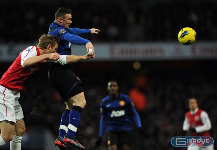 Mertesacker nhảy lên tranh bóng với Rooney trong khu cấm địa