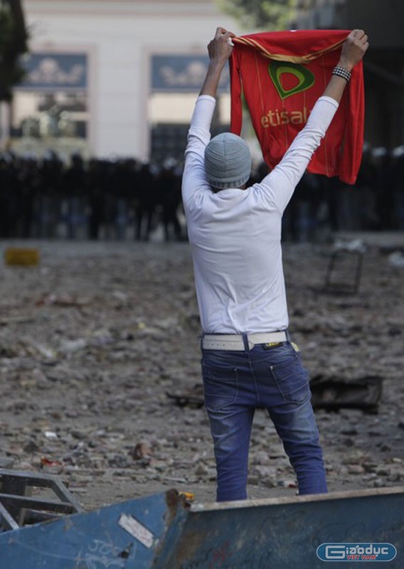 Một người Ai Cập giơ cao chiếc áo thi đấu bóng đá về hướng cảnh sát