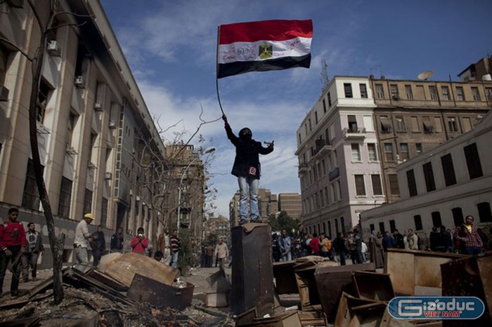 Mặc cho đống đổ nát, người đàn ông trèo lên cột và vẫy cao lá quốc kỳ như thể hiện ý chí của những người Ai Cập yêu tự do