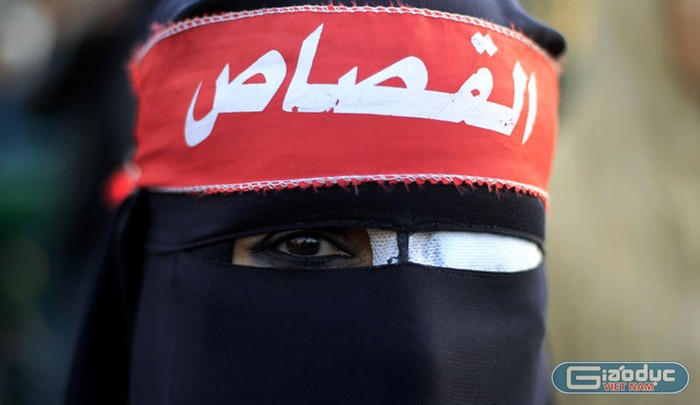 Một người phụ nữ Ai Cập đeo một miếng vá mắt cùng tấm băng đầu có dòng chữ “trừng phạt”