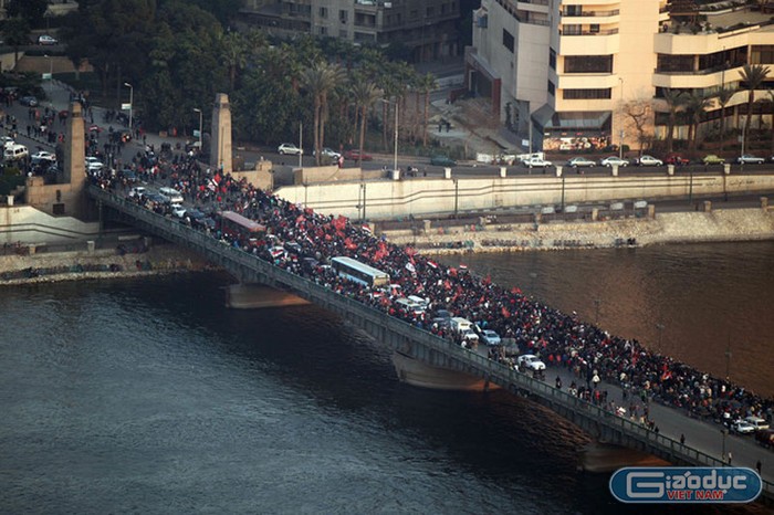 Góc nhìn từ xa cảnh đoàn biểu tình tiến đi trên cây cầu mùng 6/10, ngày lễ kỷ niệm của Lực lượng vũ trang Ai Cập. Trớ trêu thay khi gần 10.000 người đang biểu tình phản đối những người thực hiện nhiệm vụ giữ gìn trật tự trị an.