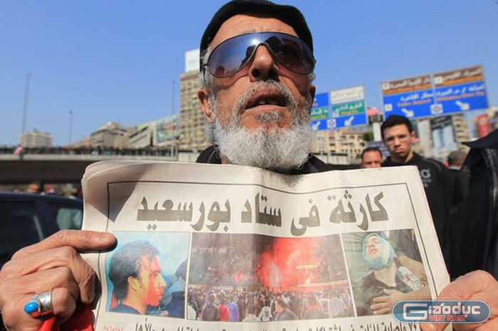 Một người biểu tình giơ tờ báo có dòng tít “Thảm họa ở sân vận động Port Said”