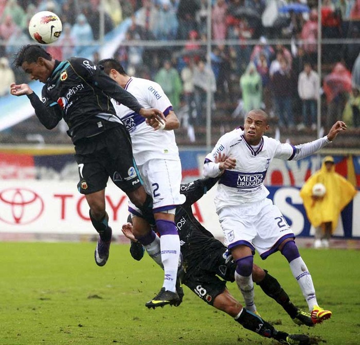 Fidel Martinez (Deportivo Quito) thực hiện cú đánh đầu trong lúc bị các cầu thủ của Defensor Sporting ngăn cản.