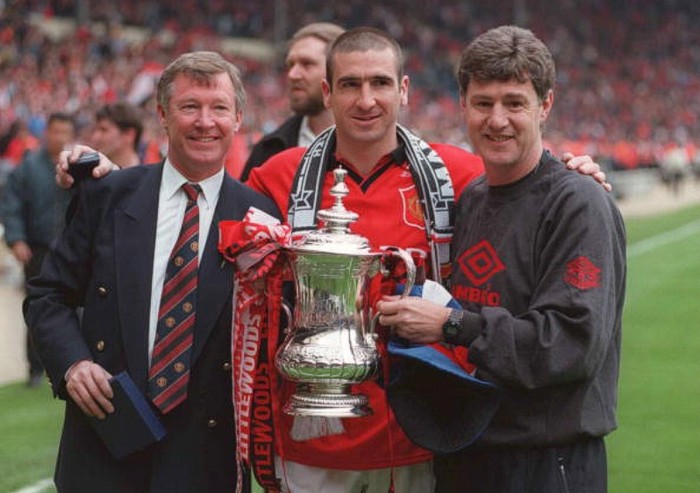 11/5/1996. Alex Ferguson (trái), Eric Cantona cùng trợ lý Brian Kidd bên chiếc cúp FA. Manchester United đánh bại Liverpool 1-0 nhờ bàn thắng muộn của Cantona.