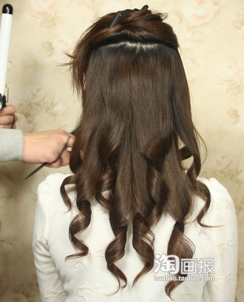 Đầu tiên lấy một phần tóc phía trên buộc cao, phần tóc phía dưới dùng máy uốn tóc uốn xoăn thành từng lọn to.
