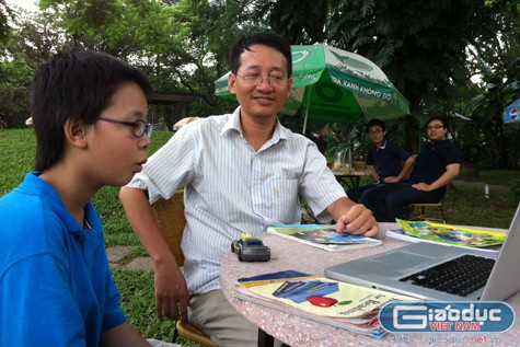Anh Kiên và bé Khang đang theo dõi video bài giảng do nhà trường gửi từ Mỹ về Việt Nam. Ảnh: Hương Giang.