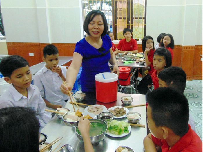 Cô giáo Hoàng Thị Lương, Hiệu trưởng Trường Khiếm thính Hải Phòng chăm sóc bữa ăn trưa cho học sinh (Ảnh: Tuyết Mai)