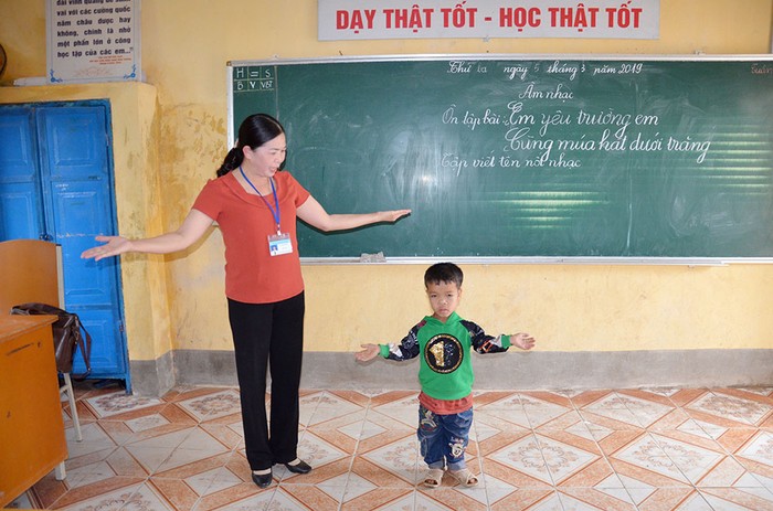 Cô giáo Lã Thị Nhung dạy môn âm nhạc cho em Vi Xuân Cảnh, học sinh lớp 3 bị khuyết tật (Ảnh: Lan Anh)