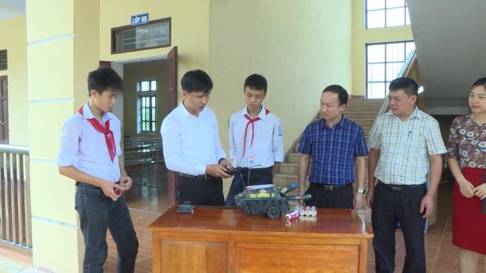 Thầy giáo Nguyễn Năng Khương (áo trắng) cùng các em học sinh nghiên cứu, chế tạo máy móc (Ảnh: CTV)