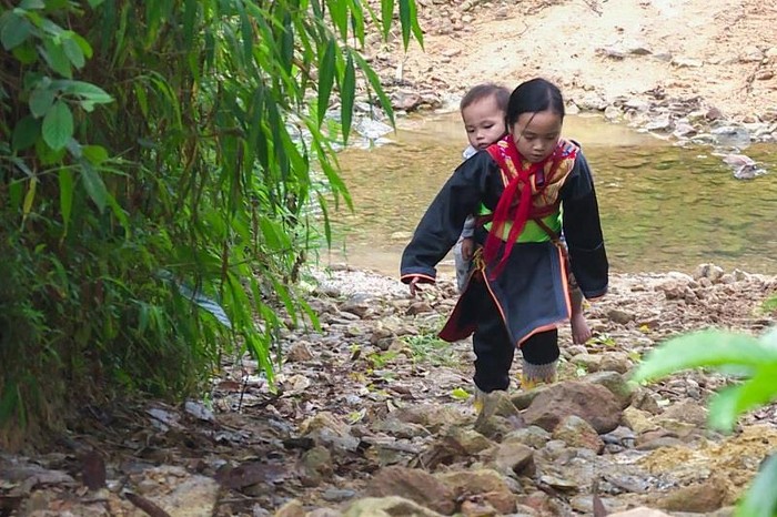 Mỗi ngày, Trình Thị Lan địu em trai trên lưng đi bộ hơn 3km tới trường (Ảnh: Hoài Minh)