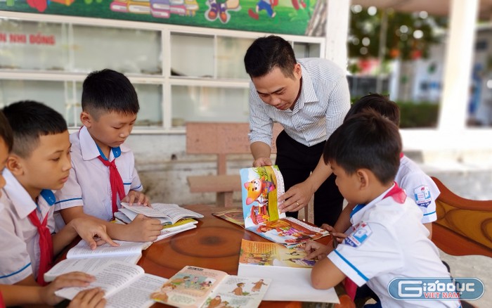 Thầy giáo Nguyễn Văn Bình hướng dẫn các em học sinh lựa chọn, đọc sách (Ảnh: Lã Tiến)