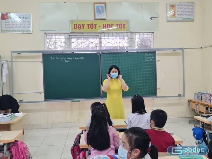 Giáo viên Trường Tiểu học Nguyễn Tri Phương hướng dẫn học sinh đeo khẩu trang đúng cách (Ảnh: Lã Tiến)