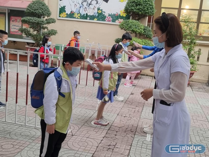 Học sinh Trường Tiểu học Đinh Tiên Hoàng được đo thân nhiệt trước khi vào lớp (Ảnh: Phương Linh)