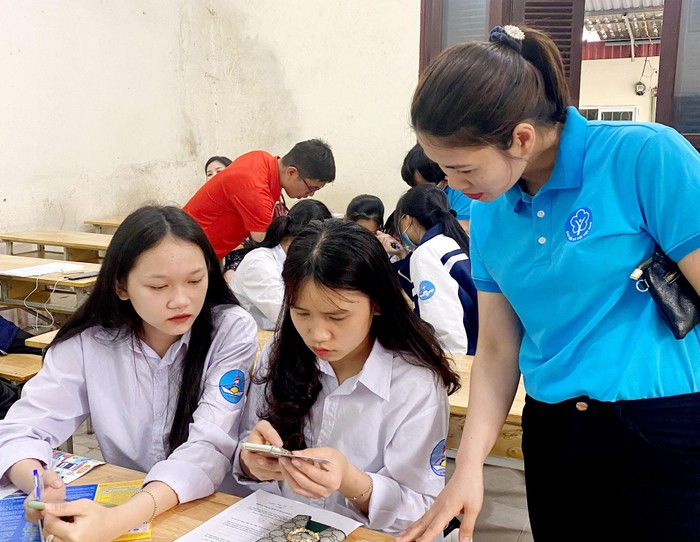 Cán bộ Bảo hiểm xã hội thành phố Móng Cái hướng dẫn học sinh cài đặt ứng dụng VssID trên điện thoại (Ảnh: CTV)