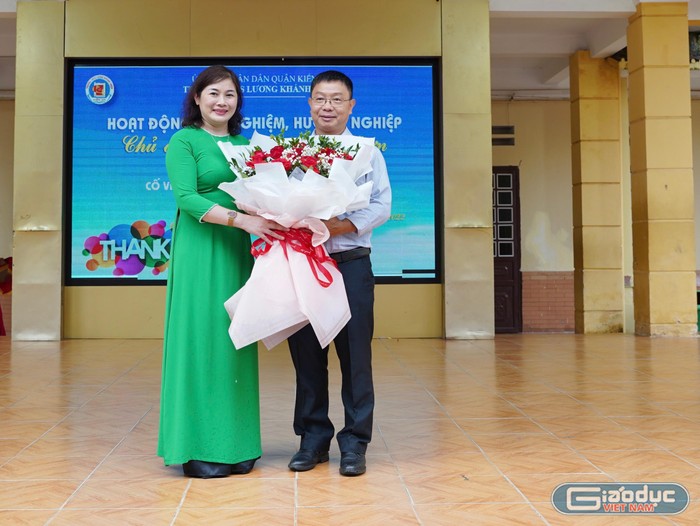 Cô giáo Nguyễn Thị Tuyết Lan - Hiệu trưởng Trường Trung học cơ sở Lương Khánh Thiện tặng hoa thầy Nguyễn Thành Nhân trước cuộc trò chuyện về lòng biết ơn (Ảnh: LT)